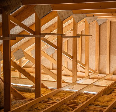 Wooden attic framing with exposed beams, insulation on the floor, and natural light coming through the roof—expertly crafted by Pantheon Roofing, a trusted name in Florida for quality construction.