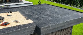 A flat roof in Florida is partially covered with black waterproofing material; Pantheon Roofing tools and supplies are visible on the exposed area.